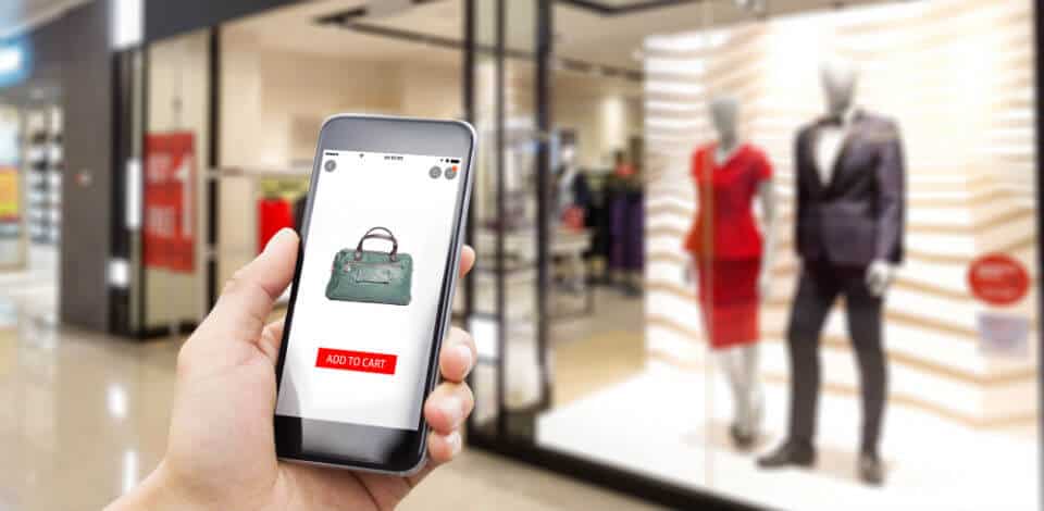 hand met smartphone met webshop solden bij kledingzaak